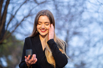 Low angle view of smiling young woman against sky