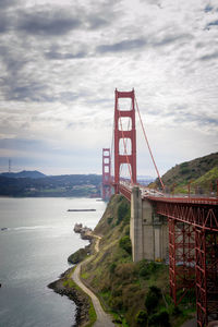 Golden gate bridge over river against cloudy sky