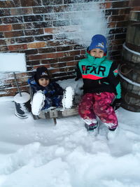 Full length of boys sitting on snow