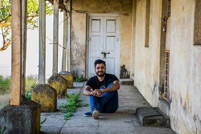 Full length portrait of young man sitting in corridor