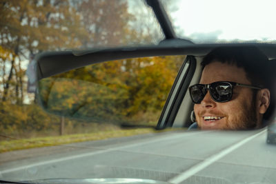 Reflection of man photographing on car