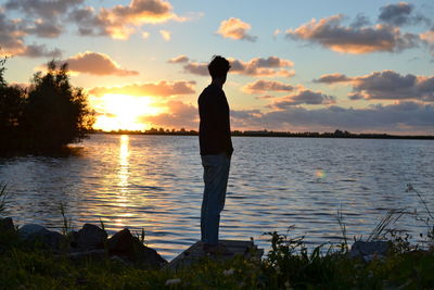 Silhouette man standing by sea against sky during sunset