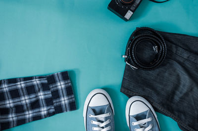 High angle view of jeans with belt and shoes on table