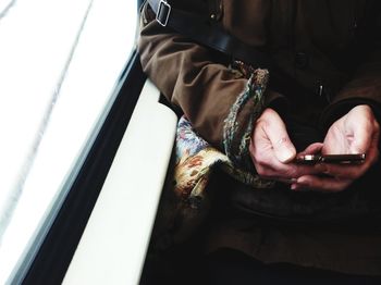 Cropped image of woman using phone while sitting in train