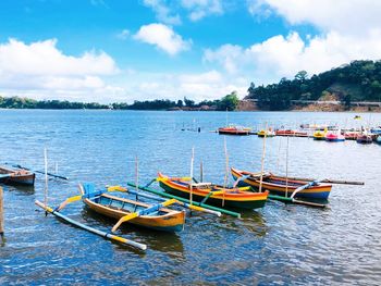 Sailboats moored in lake against sky