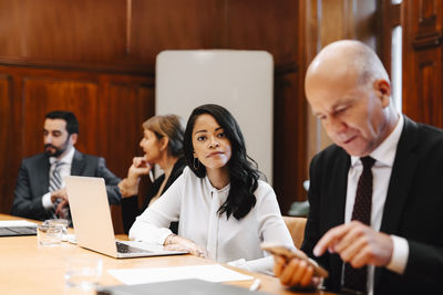 Portrait of confident female lawyer in board room with colleagues during meeting