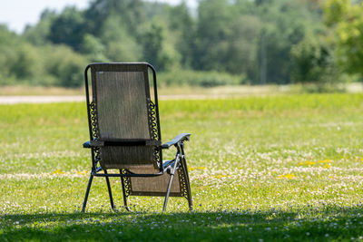 Empty chair on field in park