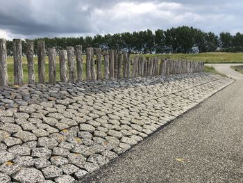 Stone wall by trees against sky