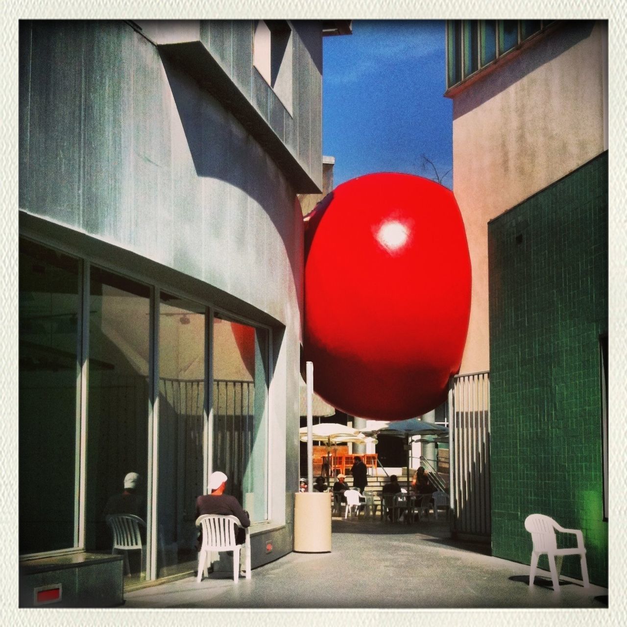 architecture, built structure, building exterior, transfer print, auto post production filter, city, sunlight, hanging, red, day, window, outdoors, building, chair, no people, in a row, shadow, restaurant, railing, sky