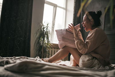 Side view of woman sitting on bed