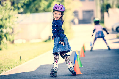 Portrait of cute girl roller skating on footpath