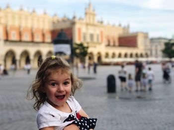 Portrait of smiling girl standing against central market square of old town krakow