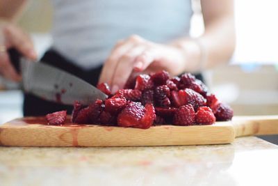 Midsection of woman cutting strawberries on board