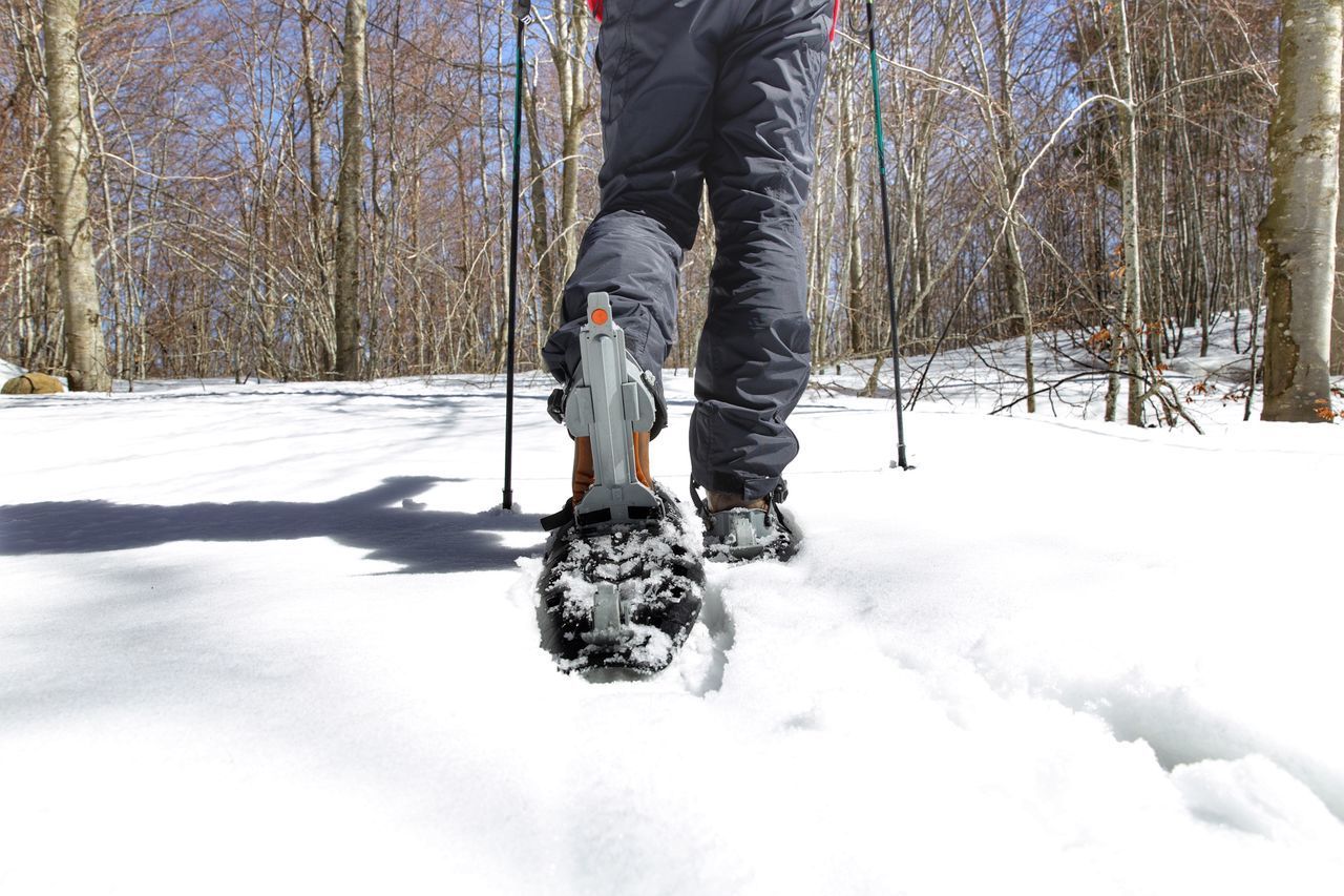 LOW SECTION OF MAN WALKING ON SNOW COVERED LAND