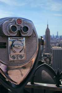 Close-up of coin-operated binoculars against empire state building and city