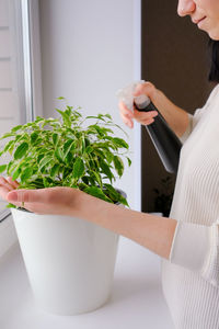Midsection of woman standing by potted plant