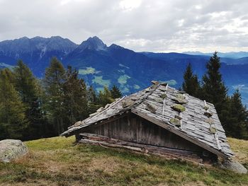 Built structure by trees on field against sky