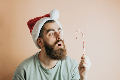 Surprise man looking at candy cane against wall