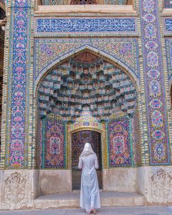 Rear view of woman standing against wall of building