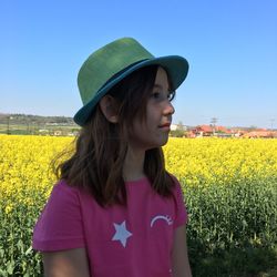 Beautiful young woman standing by yellow flower on field