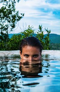 Portrait of man in swimming pool against lake