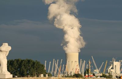 Smoke emitting from factory against sky