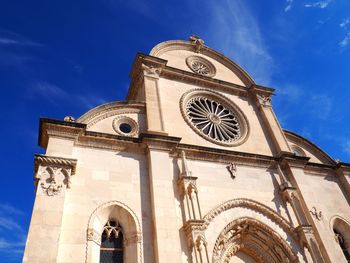 Low angle view of clock tower amidst buildings against sky