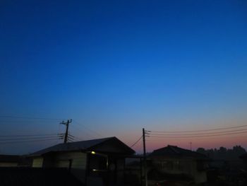 Houses against clear blue sky during sunset