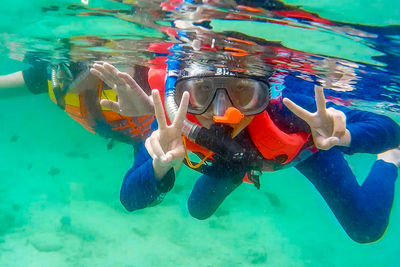 Portrait of person showing peace sign while snorkeling in sea