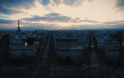 Mid distance view of eiffel tower amidst cityscape against sky during sunset