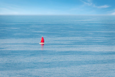 Aerial view of a sailboat with a red sail among the open sea. summer vacation yacht activity. 