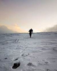 Man on snow covered land against sky