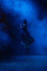 Full length of woman dancing on stage amidst smoke