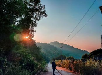 Rear view of man on mountain against sky during sunset