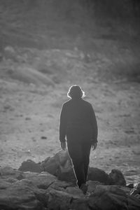 Rear view of silhouette man standing on rock