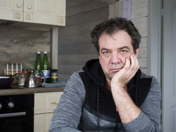 Portrait of mature man sitting in kitchen at home