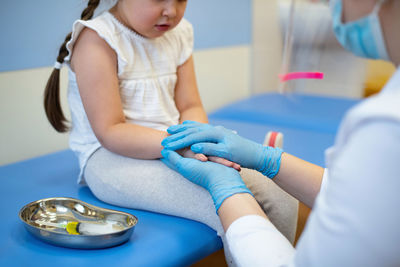 Midsection of doctor consoling girl in hospital