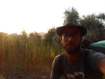 Portrait of young man wearing eyeglasses against trees