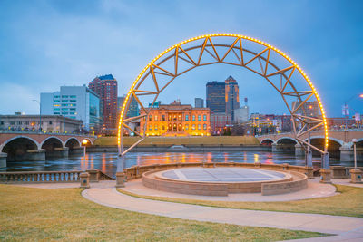 Bridge over river by buildings against sky in city