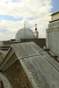 View of building roofs against cloudy sky