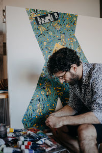 Man with watercolor paints on table sitting at home