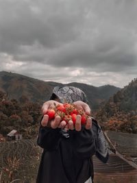 Midsection of woman holding umbrella against mountain