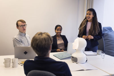 Business people discussing robot voice assistant during meeting