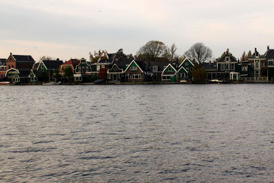 Scenic view of river by buildings against sky