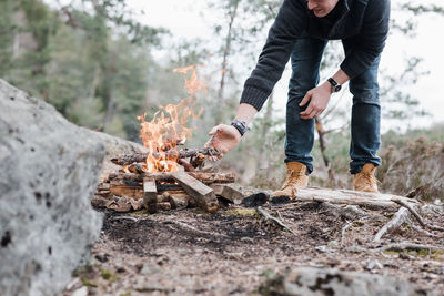 Man putting sticks on a campfire outdoors in sweden