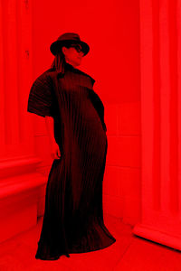 Full length of woman wearing dress while standing in red room