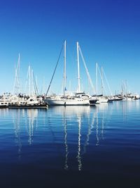 Sailboats in sea against clear blue sky