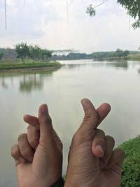 Cropped image of person hand by lake