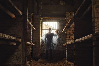 Rear view of man wearing raincoat standing in abandoned building