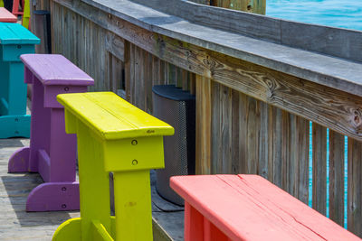 Colorful wooden benches on a wooden pier by the ocean. 